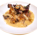 A white plate with chicken and mushrooms on it.